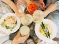 Vänner skålar med drinkar och njuter av en härlig milano mat-upplevelse med sallad och pasta med sparris.