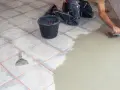Hand verputzt Fliesen mit Spachtel und Mörtel. Ein Eimer und Werkzeug liegen bereit.