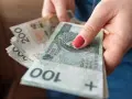 Dłoń trzyma stos polskich banknotów 100 i 200 zł. Pieniądze mogą być przeznaczone na przelew podatkowy.