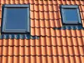 Dwa małe okienka w dachu z dachówki ceramicznej.