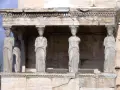 Sześć kamiennych kobiet, każda jako kariatyda, podtrzymuje architraw.