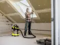 Man med skyddsutrustning använder Kärcher WD 6 för att dammsuga vid renovering av ett vindsrum.