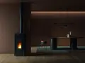 Un poêle à granulés dégage une douce chaleur, la flamme danse dans la chambre de combustion. La température ambiante est agréable, la fumée s'échappe par la cheminée.