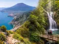 Sentiero fiorito con vista sul Vesuvio e cascata in Campania. Due escursionisti su un ponte ammirano la natura.