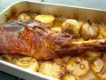 Chuletas de cordero asadas con patatas y ajos en una bandeja.
