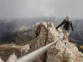 Kobieta w kasku i uprzęży pokonuje via ferrata, czyli ubezpieczoną trasę w skałach. Widok zapiera dech w piersiach!
