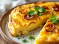 Une part de tortilla au four, dorée et garnie d'oignons caramélisés et de persil frais, sur une assiette.