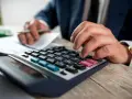 Man con traje calculando en calculadora. Los suplidos llevan IVA, un detalle importante en la contabilidad.