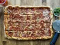 Domowa pizza na blachę z pepperoni, posypana parmezanem. Idealna na rodzinne spotkanie.