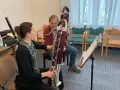 Kobieta i mężczyzna ćwiczą grę na fagotach. Jaki to instrument? Dwa duże, drewniane instrumenty dęte drewniane, fagot, są w centrum uwagi.