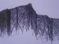 Une œuvre d'art contemporain défie la perception avec un réseau complexe de lignes sombres formant une structure abstraite rappelant une montagne ou une cascade.