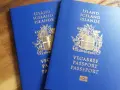 Dwa niebieskie paszporty Islandii leżą na drewnianym blacie. Czy na Islandię jest potrzebny paszport? Tak, to dokument podróży.