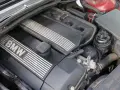 Silniki BMW E46, widok z góry na czarną pokrywę z napisem BMW i srebrnymi paskami. Widać też elementy układu dolotowego i zbiorniczek płynu.
