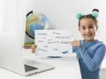 Uśmiechnięta 7 latek pokazuje kartkę z angielskimi słówkami: "English", "Hello", "Thank you!".