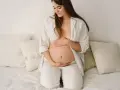 Donna incinta accarezza il pancione, con un sorriso dolce. Un momento di serenità, pensando al **sepermanente in gravidanza**.