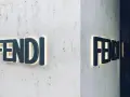 Insegna luminosa Fendi su una parete di marmo. Il **Fendi significato** è lusso e artigianalità italiana.