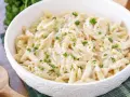 Penne w kremowym sosie śmietanowym, posypane świeżą natką pietruszki. Idealne na szybki obiad.
