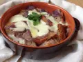 Zuppa di cipolle toscana fumante, con crostini dorati e formaggio filante, guarnita con prezzemolo fresco.