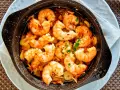 Un plato humeante de langostinos al ajillo, jugosos y dorados, nadando en aceite de oliva con ajo y perejil. ¡Un manjar irresistible!