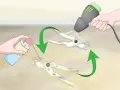 Hands spray lubricant onto pruning shears to remove rust. A heat gun is then used to dry them.