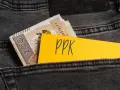 Karta z napisem "ppk" i banknoty w tylnej kieszeni dżinsów. Decyzja o rezygnacji z PPK.