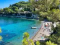 Plage idyllique à Antibes, eaux turquoise, pins parasols et villas sur la falaise. Parfait pour visiter Antibes et se détendre.