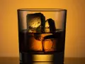 Ein Glas mit **whiskey neat**, zwei große Eiswürfel darin, beleuchtet von warmem Licht.