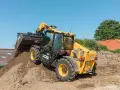 Żółty ładowarka teleskopowa JCB 525-60 z podniesionym wysięgnikiem i łyżką, pracująca na budowie.