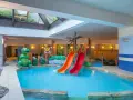 Karpacz hotel z basenem i atrakcjami dla dzieci: zjeżdżalnie, basen, zielone dinozaury i tropikalne dekoracje.