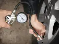 Person prüft den Reifendruck mit einem Manometer. Die warmen Reifen sind wichtig für die Sicherheit.