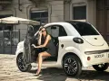 Elegancka kobieta w okularach przeciwsłonecznych wysiada z białego samochodu Microcar. Idealny samochód bez prawa jazdy na miejskie wypady.