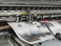 Maszyna drukarska w ruchu, tworząca strony gazet metodą wklęsłą lub offsetową.