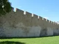 Kamienne blanki starego muru obronnego, porośnięte trawą i oświetlone słońcem.