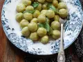 Gnocchi di zucchine morbidi e profumati, guarniti con foglie di salvia fresca su un piatto decorato.