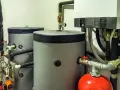Installazione scaldabagno a pompa di calore con serbatoi grigi, serbatoio rosso e caldaia bianca.