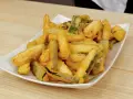 Un piatto bianco pieno di zucchine in pastella dorate e croccanti, pronte per essere gustate.