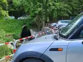 Samochody zaparkowane w dolinie małej łąki, przy strumieniu. W tle las i zielone wzgórza.