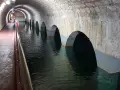 Interior de aljibes de agua abovedados, con arcos que se sumergen en el agua. Un pasillo con barandilla recorre el lateral.
