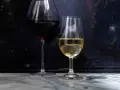 Dwa kieliszki z winem: czerwonym i białym. Białe wino, w tym wino extra dry, lśni w świetle.