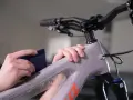 Hands apply protective film to a mountain bike frame. This bike is ready for any terrain, whether trails or roads.