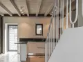 Interno moderno con travi a vista in legno, illuminazione led soffusa e una scala bianca.