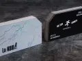 Dos pilas de papel para tarjetas de visita. Una tiene un diseño de relámpagos iridiscentes sobre fondo gris. La otra es negra con datos de contacto.
