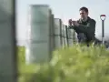 Un perito agrario lavora in un campo, piantando giovani alberi protetti da reti.