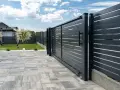 Solidny fundament pod bramę przesuwną zapewnia jej stabilność i płynne działanie. Nowoczesna, ciemnoszara brama z poziomymi lamelami.