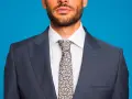 Uomo con abito blu, camicia bianca e cravatta fantasia. Un abbinamento classico per un look elegante.