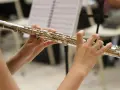 Dłonie grające na srebrnej flecie, jednym z tych mało znanych instrumentów muzycznych, na tle nut.