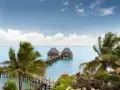 Dwa domki na wodzie z palmami w tle, idealne na spokojny wypoczynek podczas pory deszczowej na Zanzibarze.