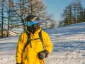 Narciarz w żółtej kurtce i goglach na tle drzew. Dowiedz się, jak prać kurtkę narciarską, by służyła latami.