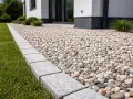 Nowy, schludny podjazd z kamyków i betonowa opaska wokół domu tworzą estetyczną całość.
