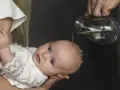 Chrzest chłopca: polewanie główki wodą z dzbanka.